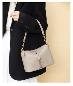 Detailed side view of grey pebbled leather shoulder bag with decorative vertical zipper