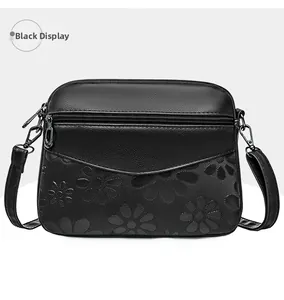 Detail of black faux leather shoulder bag featuring floral embossing and litchi texture