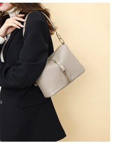 Detail of light grey pebbled leather shoulder bag with gold zippers and metal hardware