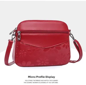 Detail of red crossbody bag with embossed daisy pattern and multi-layer silver zippers