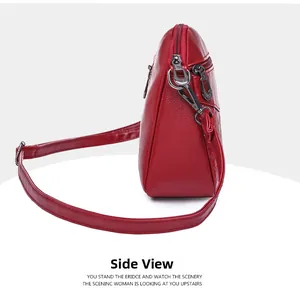 Side view of red pebble leather shoulder bag showing multi-zipper layers and hardware