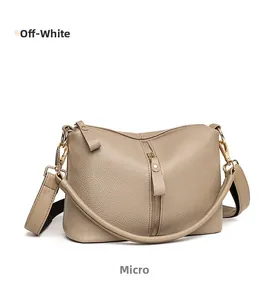 Close-up of minimalist off-white leather handbag showing lychee grain and gold zipper