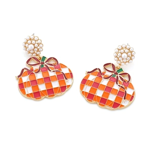 Macro view of pumpkin pendant earrings with pearl studs and colorful checkered enamel detail