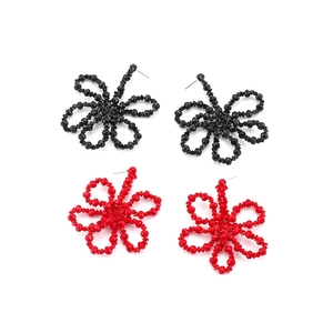 Detailed view of handmade geometric beaded flower earrings in red and black colors