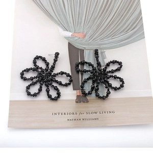 Close-up of black beaded geometric flower earrings with faceted crystal details