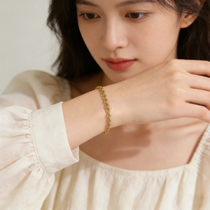 Vue détaillée d'un bracelet chaîne en acier inoxydable doré sur le poignet d'une femme