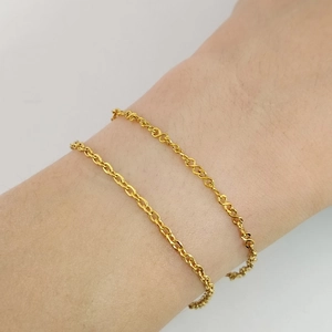Gros plan d'un bracelet à double chaîne en acier inoxydable doré sur un poignet femme