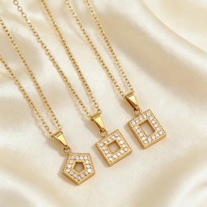 Close-up of gold geometric necklaces with zircon inlay on luxury silk fabric