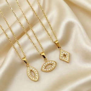 Detailed view of three gold geometric zircon pendants on champagne silk background