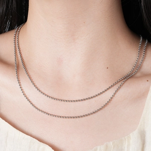 Close-up of minimalist layered stainless steel bead chain necklace worn on neck