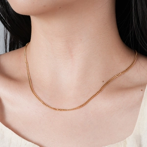 Détail d'un collier chaîne gourmette plaqué or 18 carats porté sur la clavicule féminine