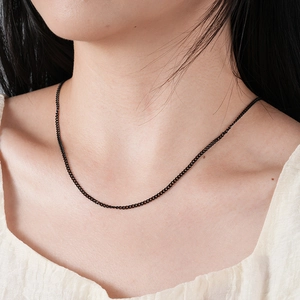 Gros plan d'une fine chaîne gourmette noire en acier inoxydable sur un mannequin