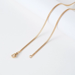 Détail d'un collier chaîne gourmette dorée avec fermoir mousqueton sur fond blanc épuré