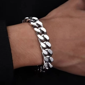 Gros plan d'un bracelet gourmette argenté en acier inoxydable sur un poignet d'homme