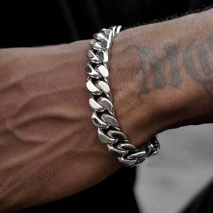 Gros plan d'un bracelet gourmette en acier inoxydable poli argenté sur un poignet
