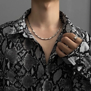 Dettaglio di una collana a corda in acciaio argento e anello a fascia minimale su un modello