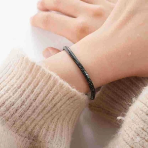Détail du bracelet chaîne serpent en acier noir sur un mannequin portant un pull beige