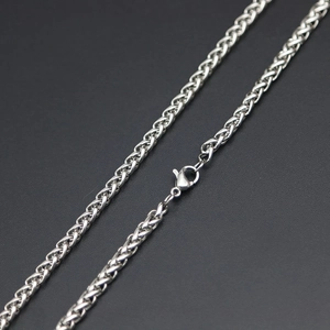 Détail d'un collier chaîne épi argentée avec fermoir mousqueton sûr sur fond gris clair