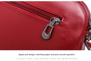 Detail of red lychee textured leather bag showing smooth gunmetal zipper and logo puller