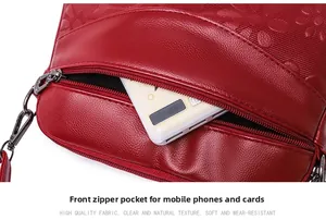 Detail view of front zipper pocket on red embossed leather bag with floral pattern