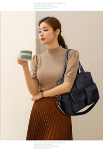 Close-up of black multi-pocket nylon tote bag worn by a model in a minimal interior