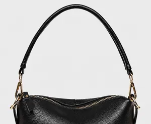 Detail of reinforced black pebbled leather handle and gold hardware on tote bag