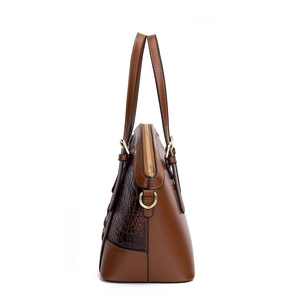 Side view of dark brown crocodile embossed shell bag with gold zipper and smooth leather trim