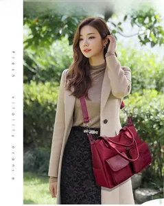 Detail of burgundy nylon tote bag with multiple zip pockets and adjustable shoulder strap