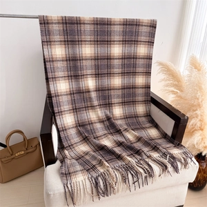 Gros plan d'une écharpe à carreaux marron vintage avec franges sur une chaise blanche