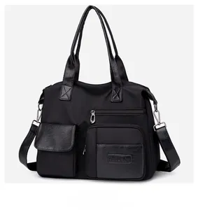 Detail of black nylon tote bag showing multiple functional pockets and silver hardware