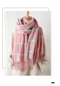 Détail d'une écharpe à carreaux rose et blanc avec franges sur un manteau crème