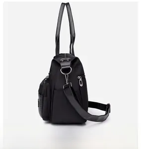 Detail view of water-resistant black nylon tote bag with leather handles and side pockets