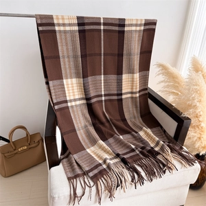 Detail of plaid cashmere-feel scarf with soft fringe and warm brown check patterns