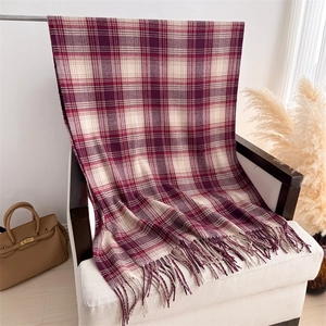 Détail d'une écharpe à carreaux et franges sur une chaise montrant la texture du tissu