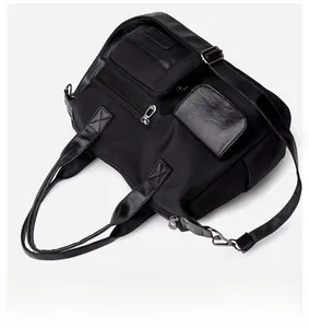 Close-up of black nylon tote bag with multiple pockets, PU leather trim, and silver hardware