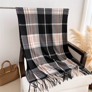 Detail of plaid scarf with black tassels on armchair featuring classic check patterns