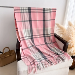 Detail of pink plaid cashmere-feel scarf with soft tassels on a white fabric chair