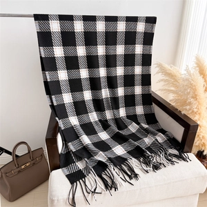 Détail d'une écharpe à carreaux style cachemire avec de longues franges et un motif noir blanc