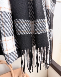 Gros plan sur l'écharpe à carreaux noir, blanc et marron avec franges et texture douce