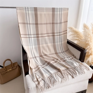 Detail of classic beige plaid scarf with soft cashmere-like texture and tassel trim