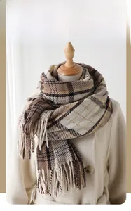 Detail of classic brown and beige checkered winter scarf with long tassels on a coat