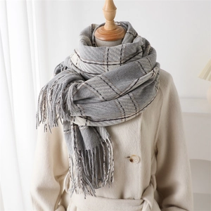 Détail d'une écharpe à carreaux gris et blanc avec franges sur un mannequin élégant