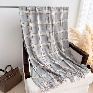 Détail d'un châle en cachemire à carreaux avec franges sur un fauteuil, style cosy