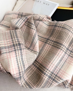 Détail de la texture d'une écharpe à carreaux épaisse en beige, rose et marron doux