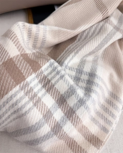 Close-up of soft plaid scarf showing thick knit texture and fringe in beige and brown
