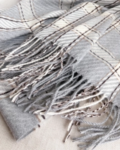 Détail de l'écharpe à carreaux gris et beige avec tissage à chevrons et franges douces