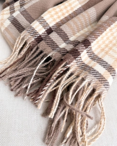Detailed view of the soft brown and beige plaid pattern scarf with long tassel fringe