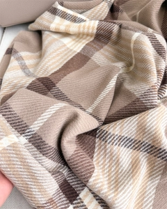 Close-up of earth-toned plaid scarf fabric showing thick twill weave texture and softness