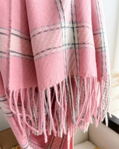 Gros plan détaillé d'une écharpe à carreaux rose doux avec franges et texture sergé