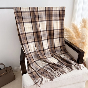 Detail of warm cashmere-feel plaid scarf with fringe on a chair in a cozy home setting